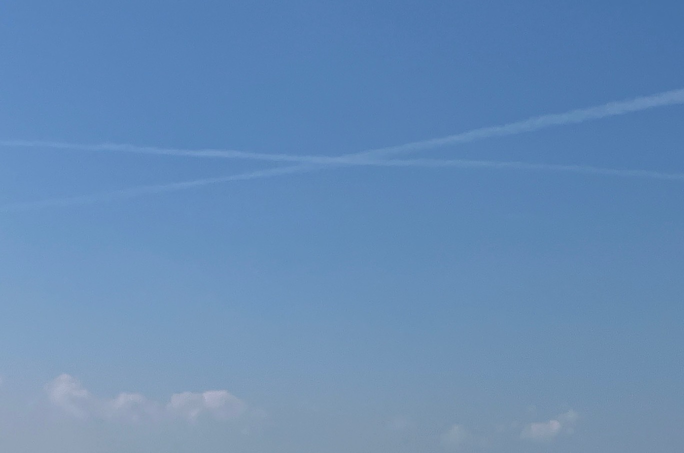 空の写真 夏の雲 画像の中心に大きなバッテン 2本の真っ直ぐな飛行機雲が交差して大きなバッテンに見えるのだ。その画像のバッテン部に寄った画像。